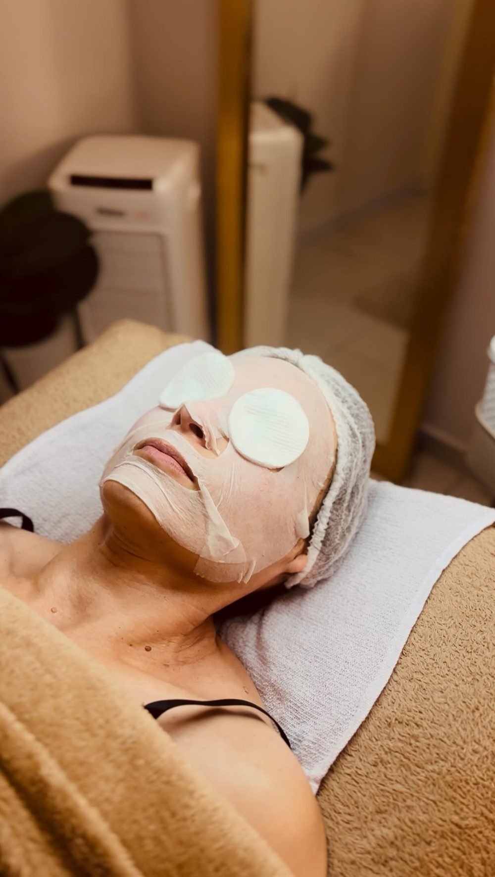 Paciente com máscara facial e protetores nos olhos durante limpeza de pele