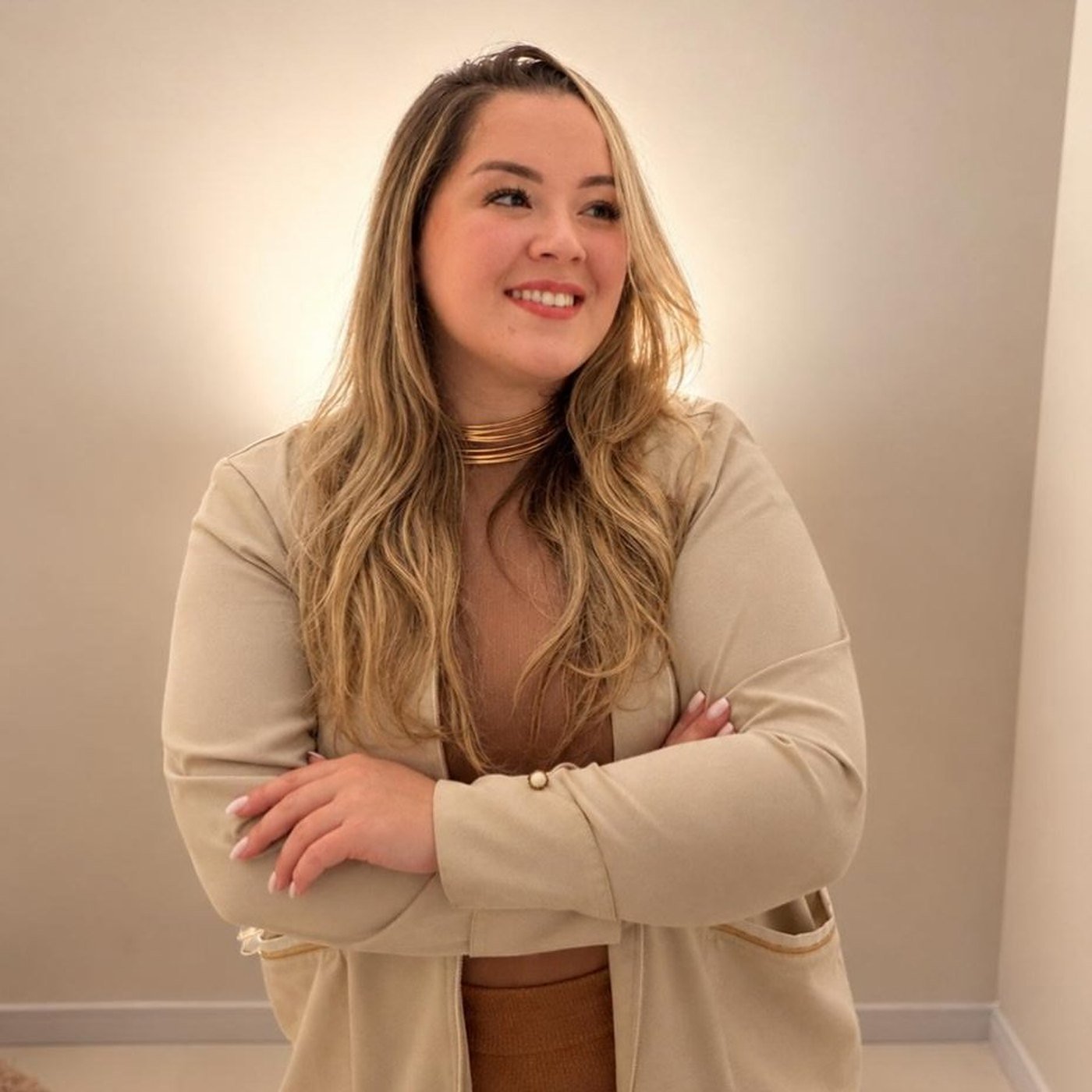 Dra. Kamilla Leidens sorrindo, de braços cruzados, com blazer claro